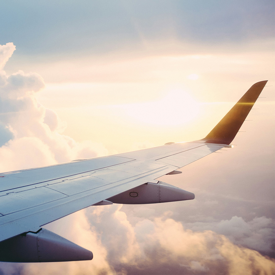 Photographie d'une aile d'avion en plein vol avec un fond de ciel bleu ensoleillé